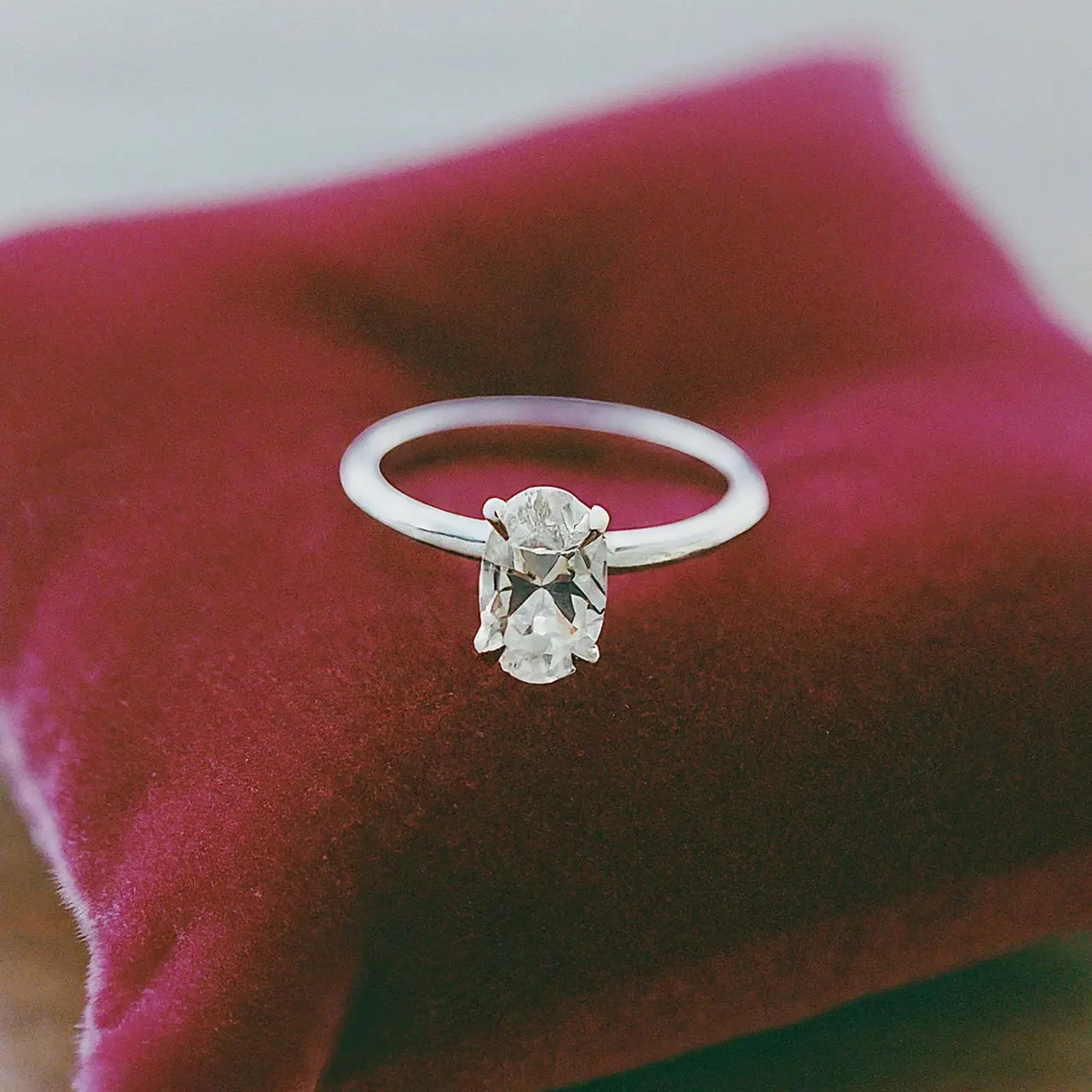 An elegant oval diamond ring on a soft, velvet cushion. 35mm stock photo