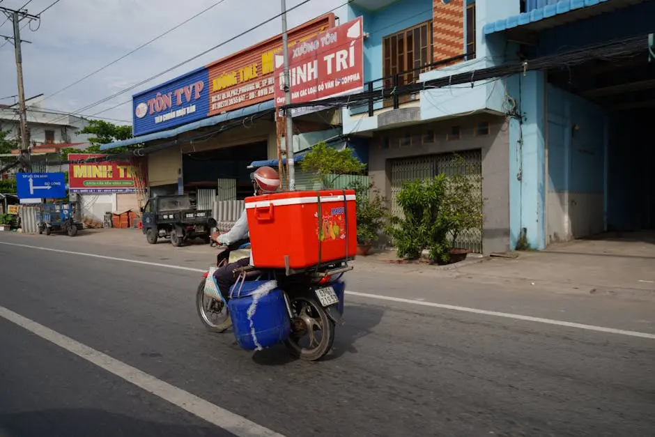 A delivery person rides a motorbike with cargo through a vibrant Vietnamese street.