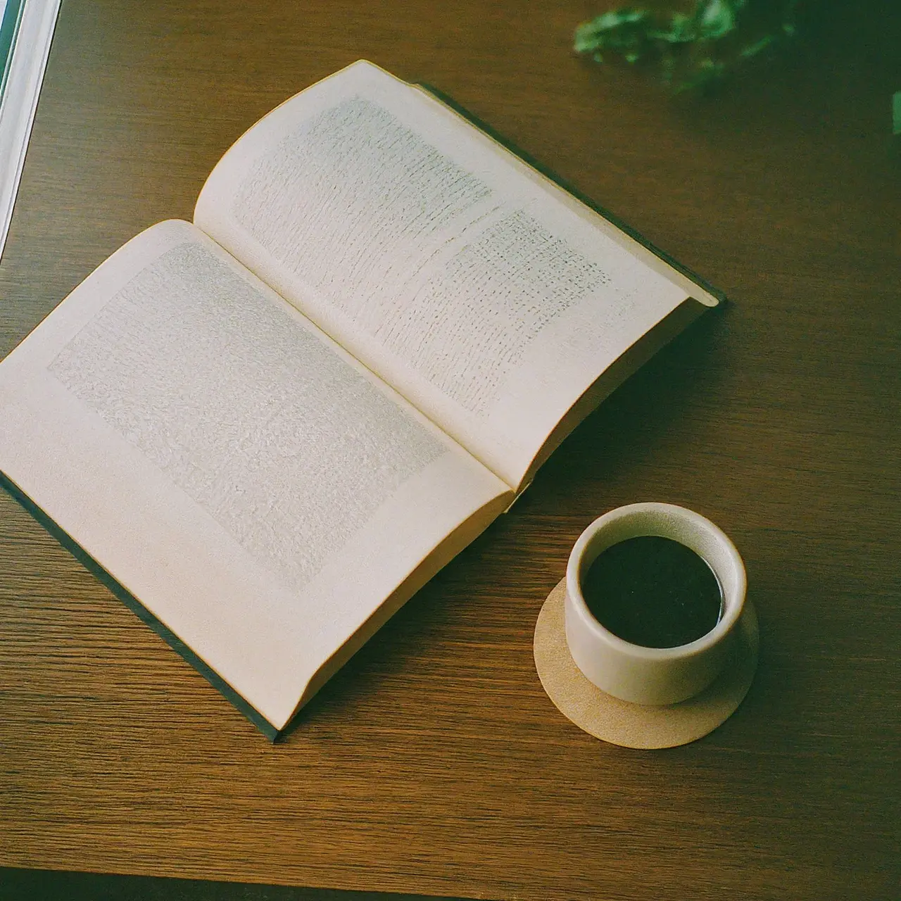 An open book next to a cup of coffee. 35mm stock photo