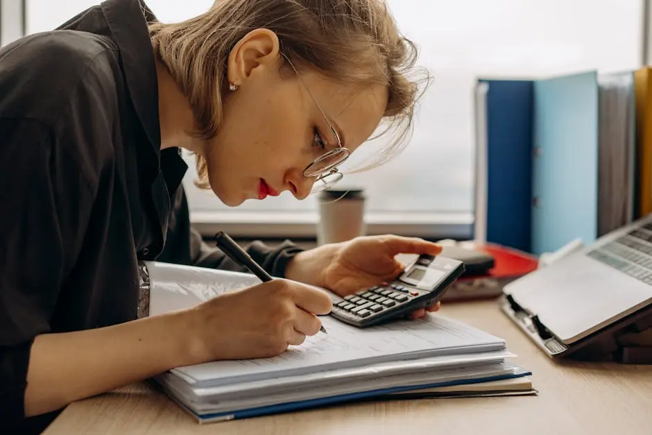 Young woman diligently working on accounting with a calculator and documents. Perfect for business and finance themes.