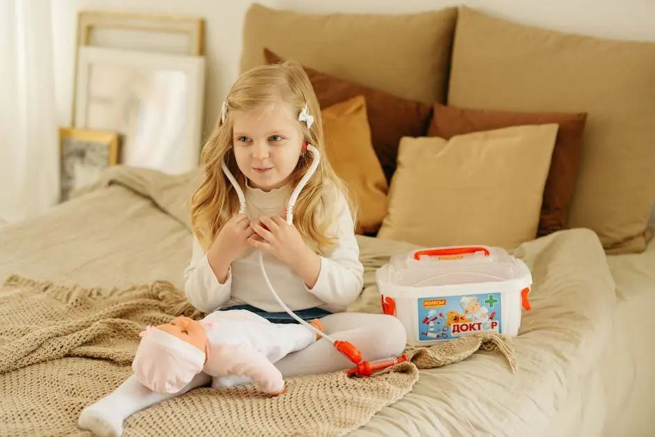 A cute child with blonde hair playing doctor on a bed with a toy stethoscope and baby doll.