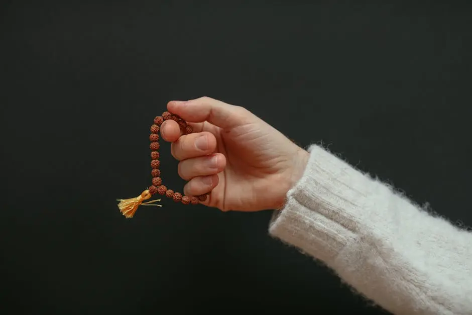 A close-up of a hand holding a beaded bracelet against a dark background.