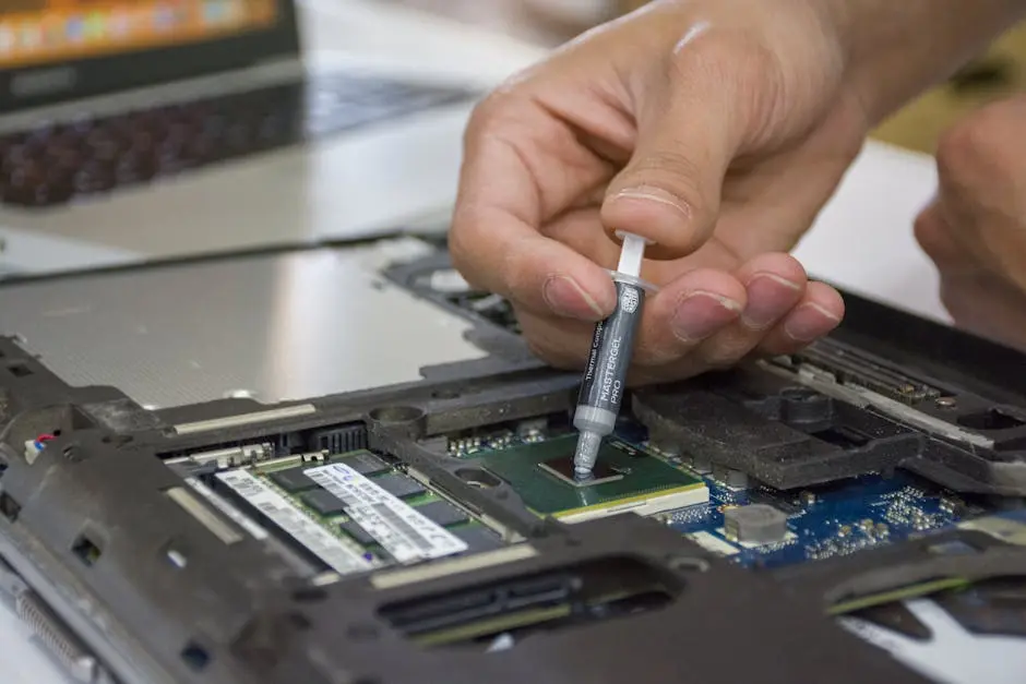 Close-up of hand applying thermal paste to a laptop microchip for maintenance.