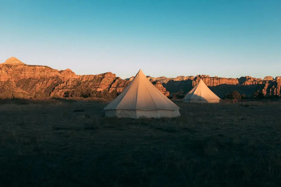 Two glamping tents in Utah desert against a backdrop of stunning red rock formations at sunset.