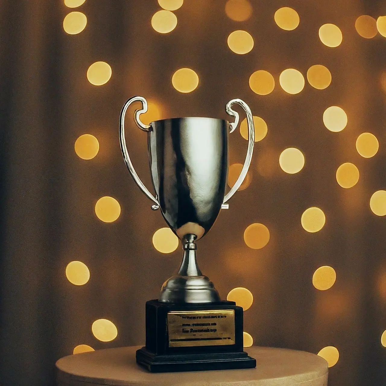 A trophy on a pedestal with shimmering lights in background. 35mm stock photo