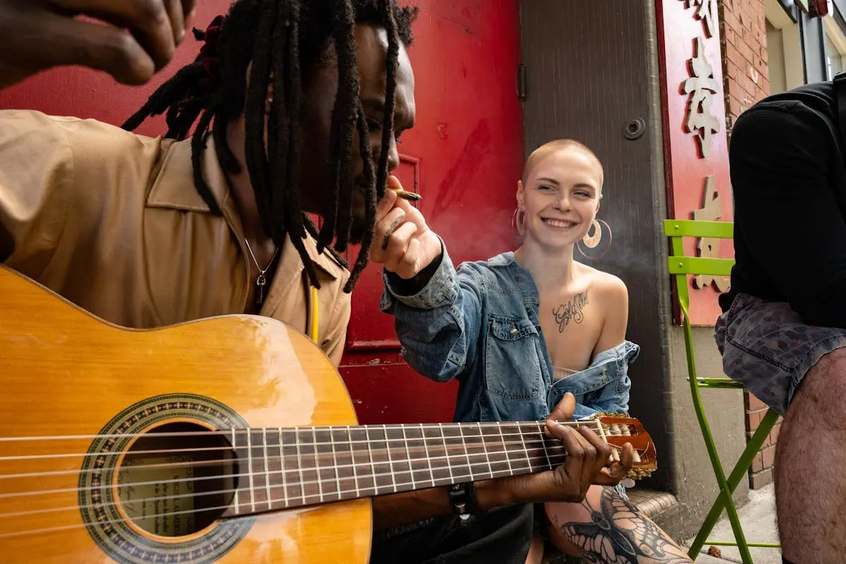 Man and Woman Sitting on Sidewalk and Playing Music