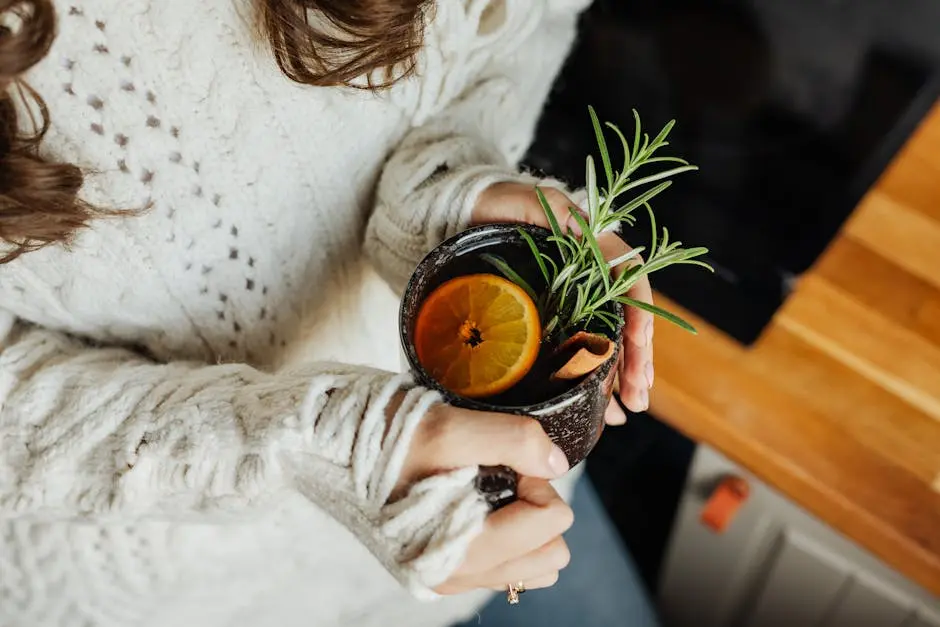 Close-up of Woman Holding a Cup of Tea with a Lemon Slice and Herbs