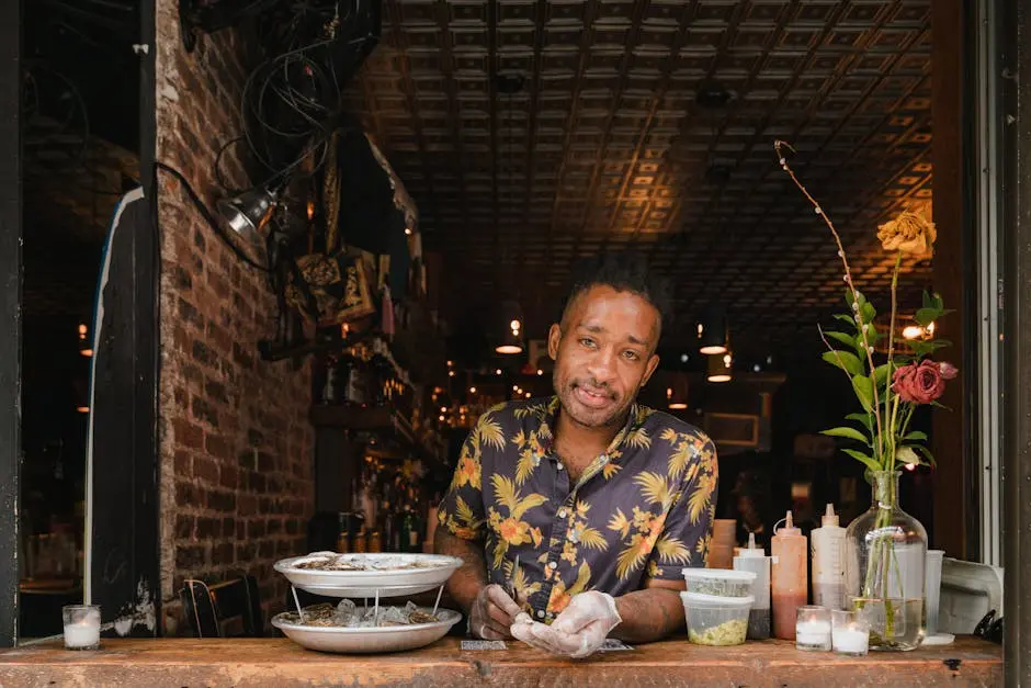 A man in a Hawaiian shirt prepares oysters at a restaurant counter, showcasing small business charm.