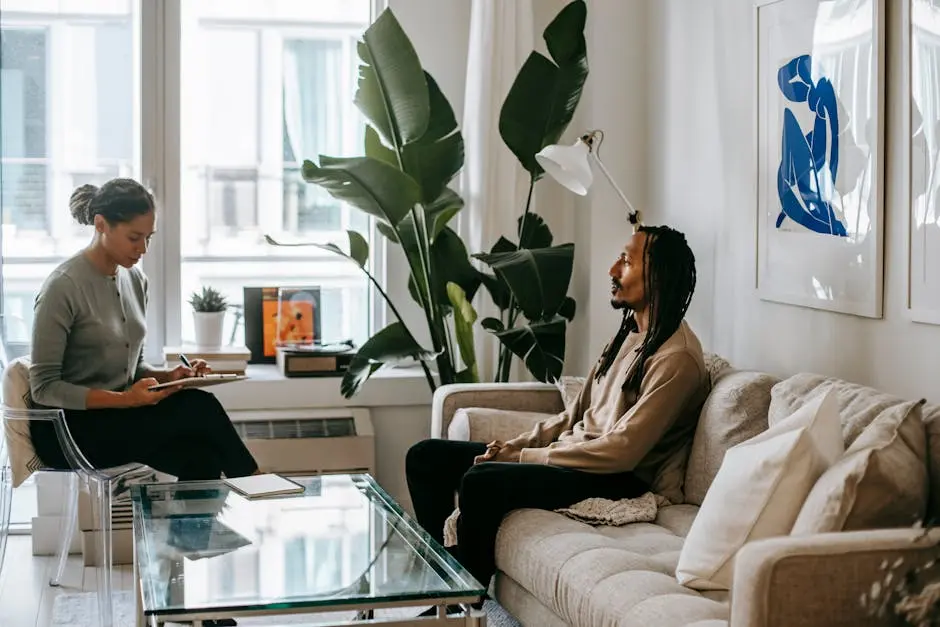 African American female taking notes on paper while speaking with male partner on sofa at home