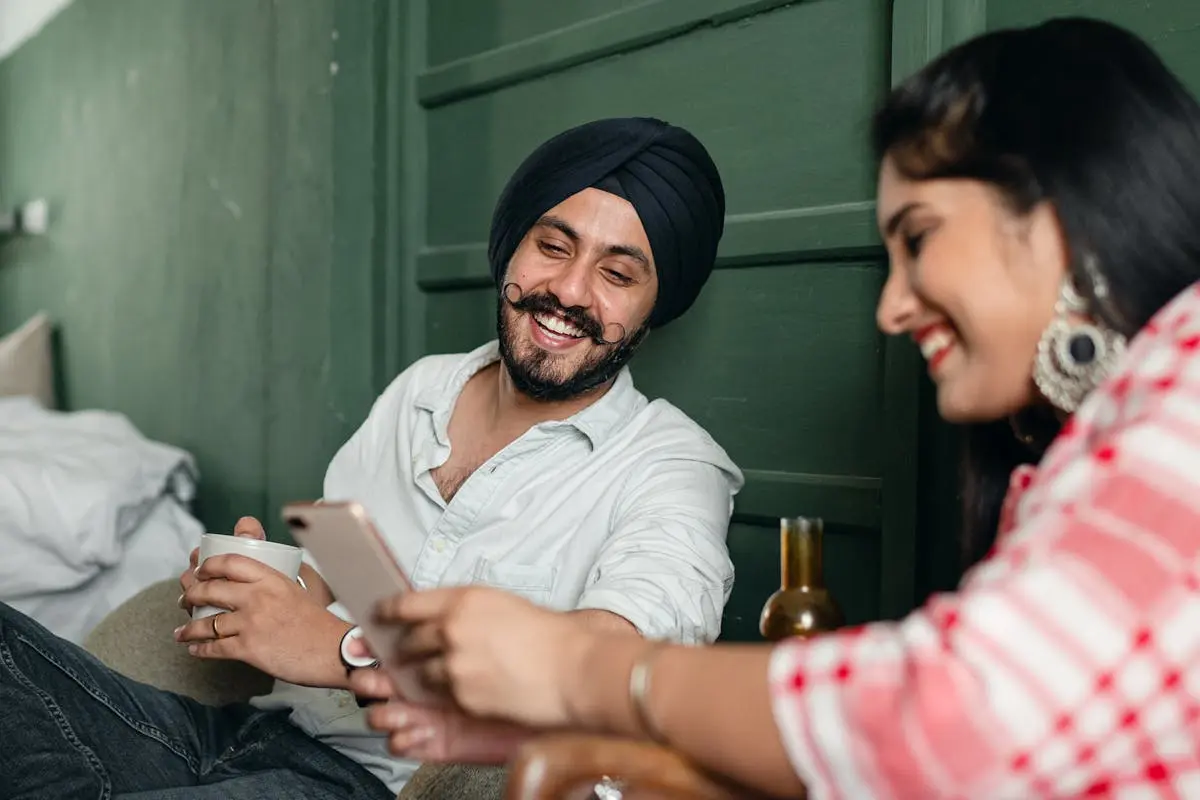 Expressive happy couple surfing smartphone and laughing