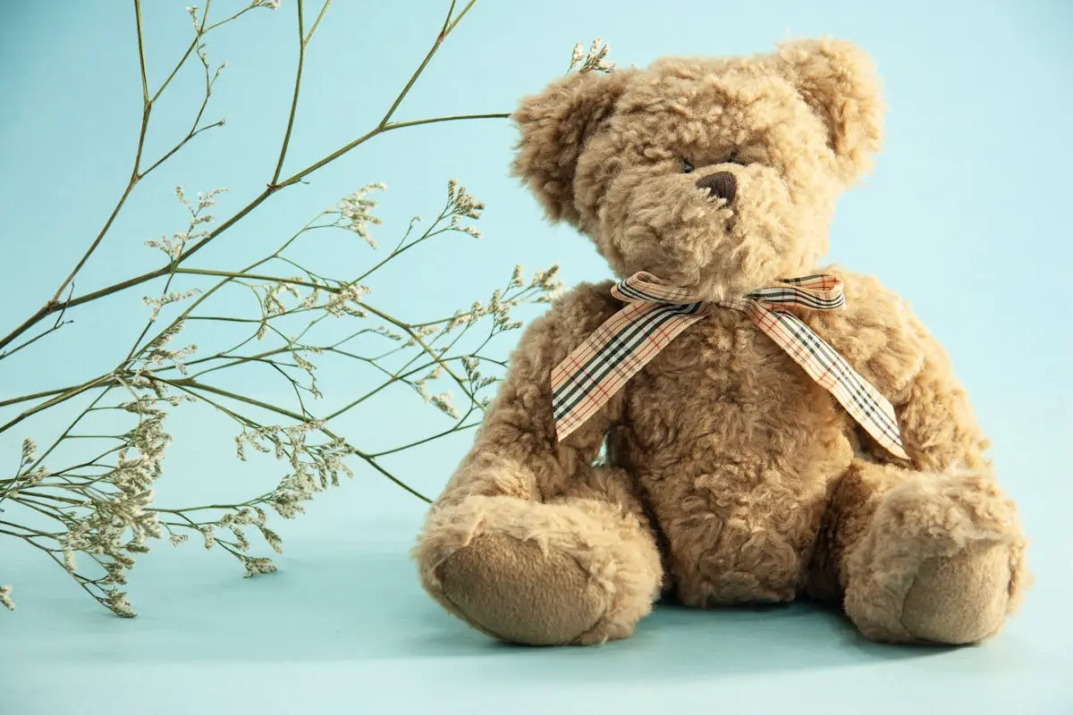 Cute stuffed animals teddy bear placed near thin sprigs of Gypsophila on blue background