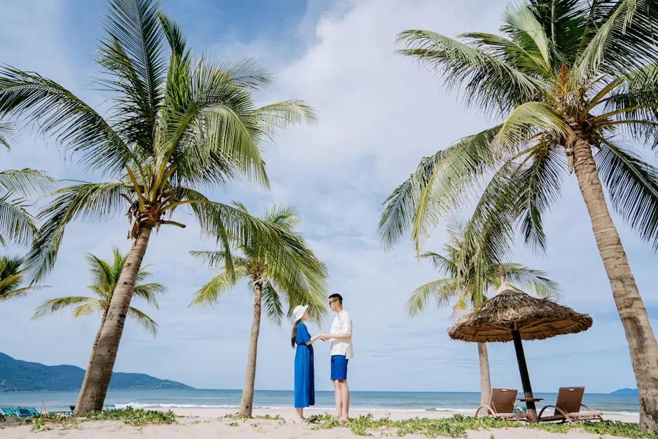 A couple holds hands on a sunny beach surrounded by coconut trees, enjoying a tropical vacation.