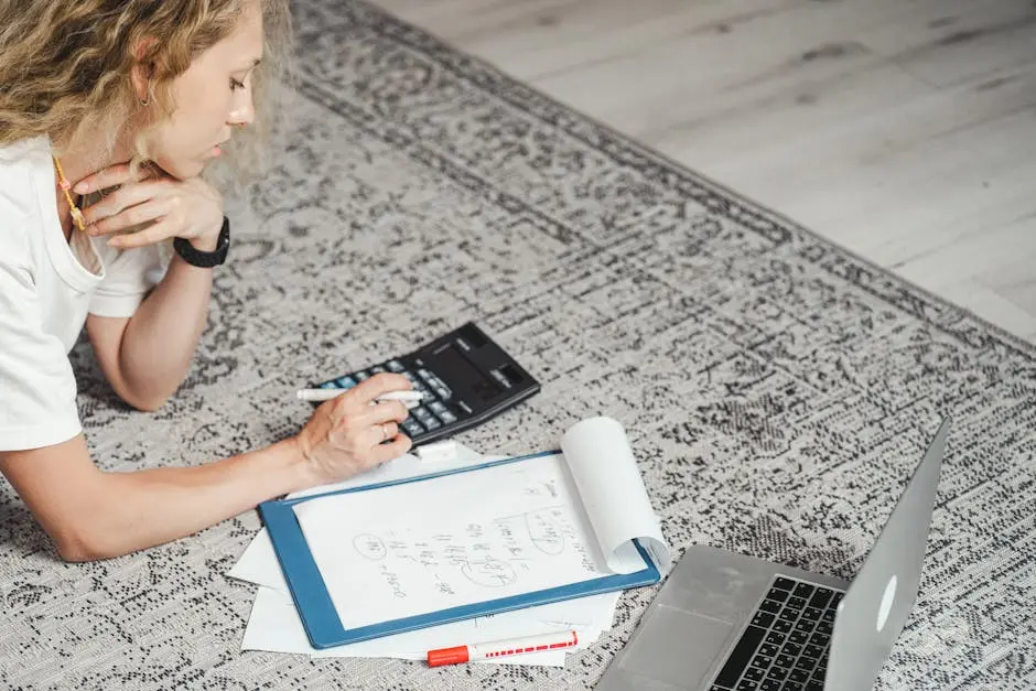 Woman Lying on the Floor with a Laptop, Documents and Using a Calculator