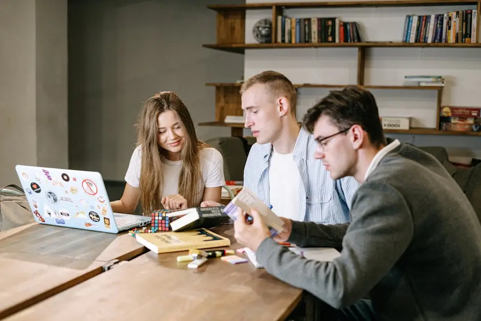 A group of young professionals collaborating on a project in a modern office space, working with books and a laptop.