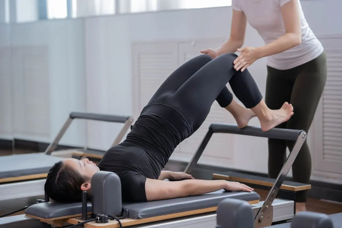 Fitness Instructor Assisting Woman Doing Pilates