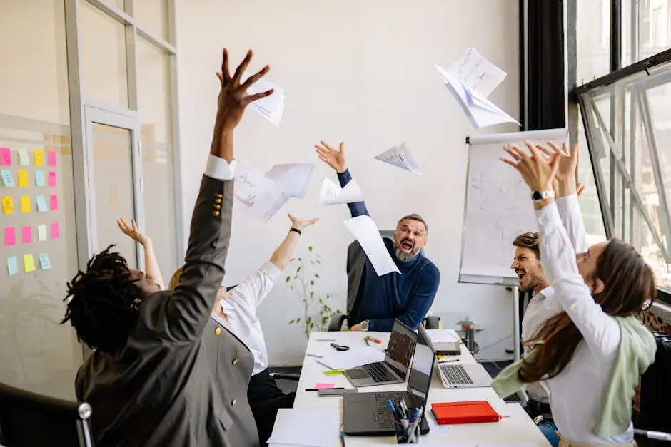 A diverse office team celebrating with papers in the air, showing teamwork and success.