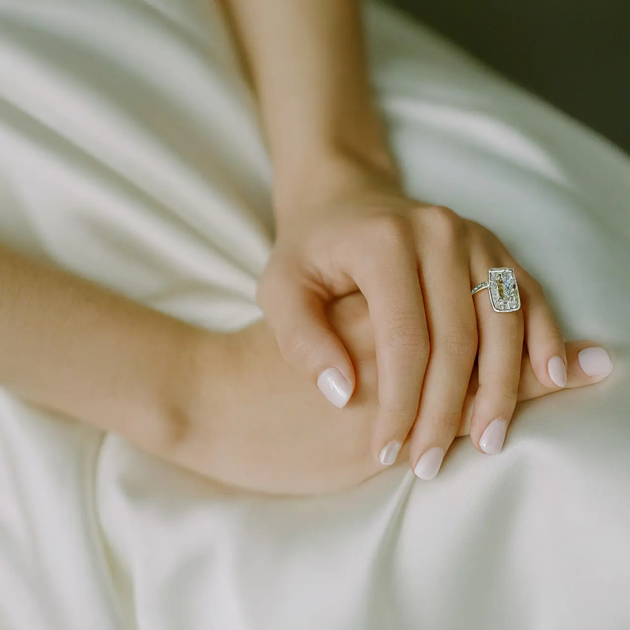 Emerald cut diamond ring on a satin bridal gown. 35mm stock photo