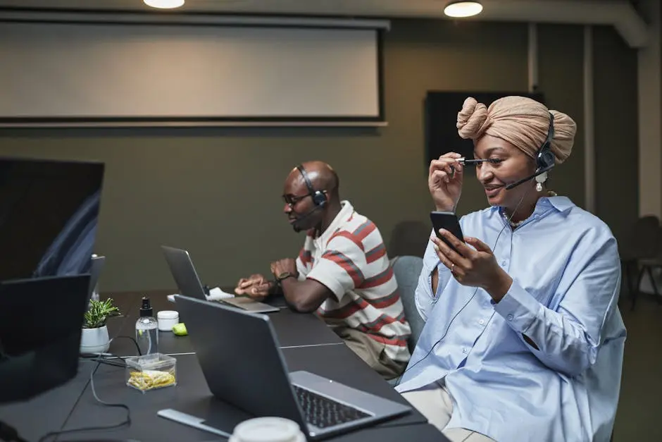 Professional call center team working at desks with laptops and headsets in a modern office environment.