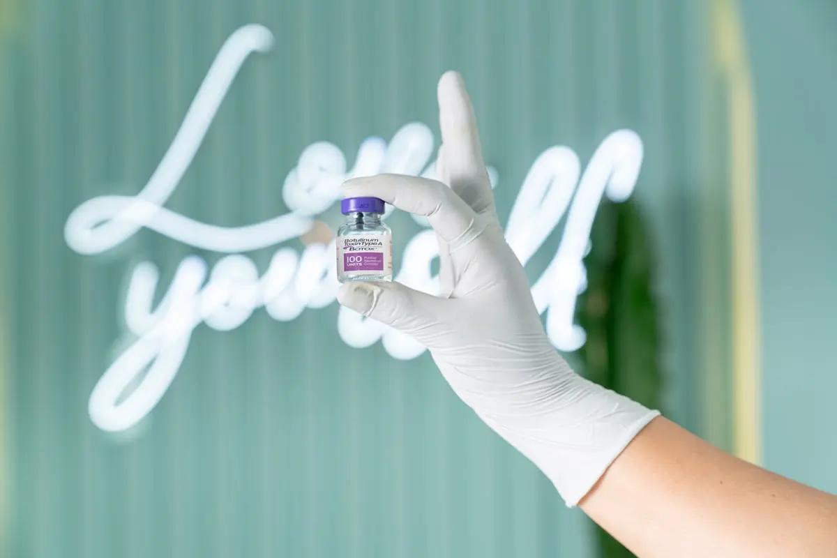 A gloved hand holding a small vial of Botox (onabotulinumtoxinA). Botox is commonly used for reducing fine lines and wrinkles, offering a non-invasive solution to combat signs of aging.