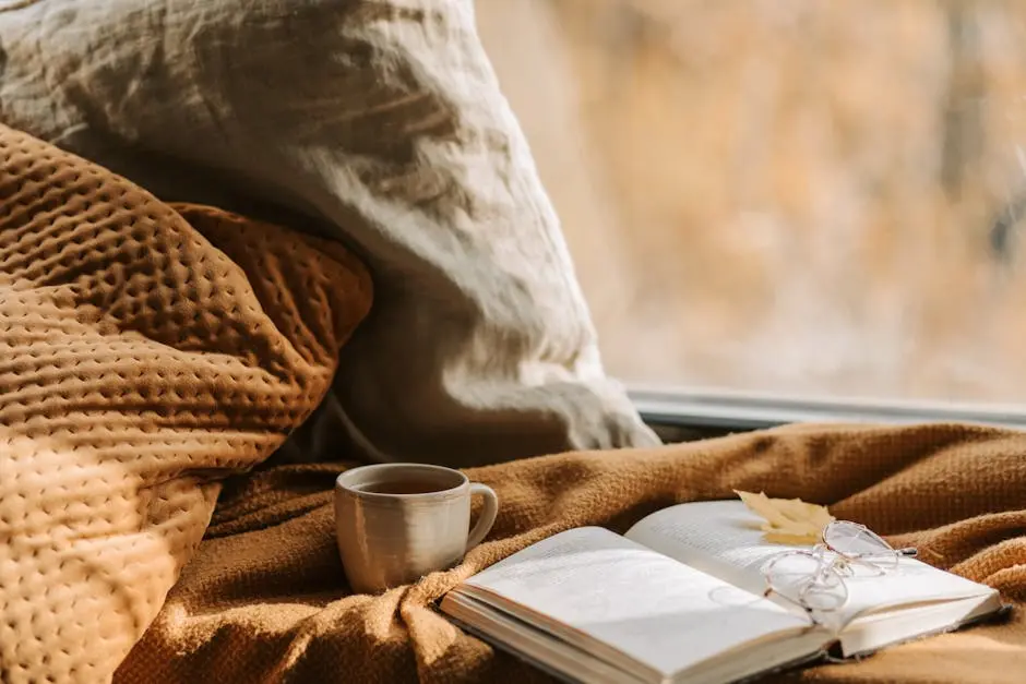 Inviting autumn scene with book, eyewear, and a warm drink by a window, perfect for relaxation.