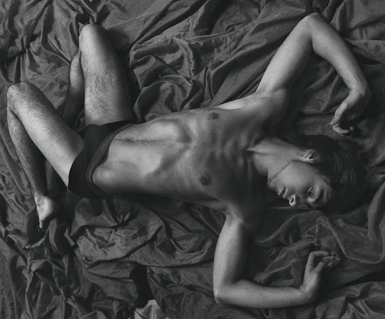 Artistic shot of a male model posing in underwear on a textured bedspread.