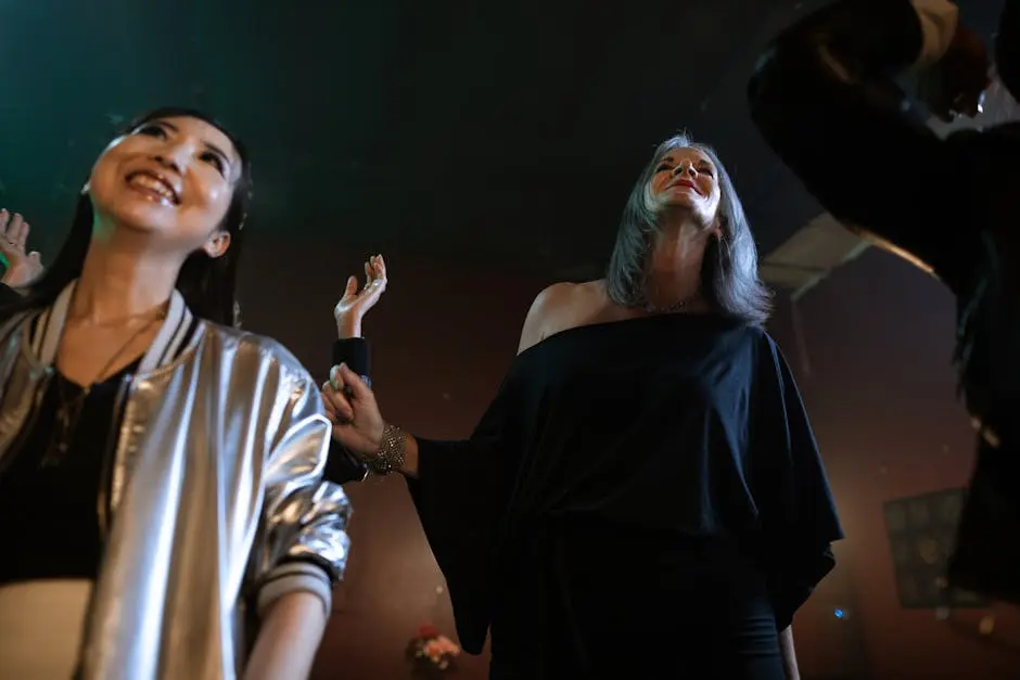 Joyful women dancing and smiling at a lively club during the night.