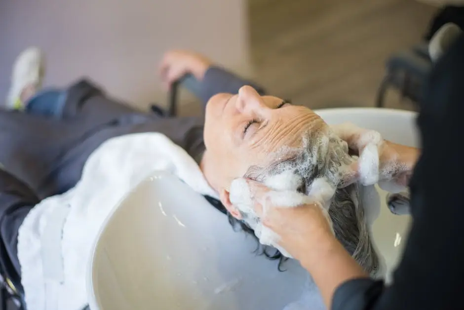 Woman enjoying a relaxing hair wash with shampoo and massage in a modern hair salon.