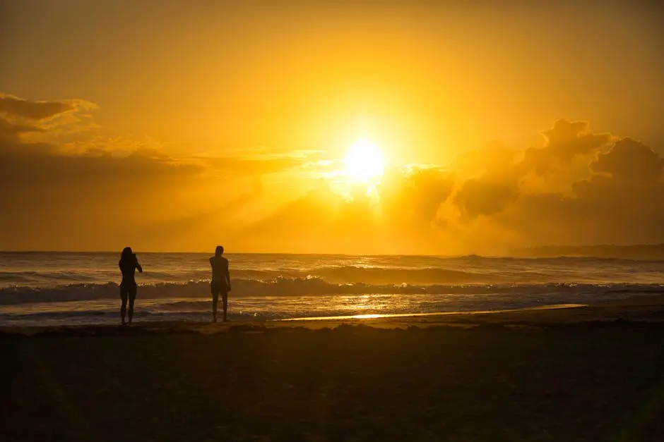 Silhouetted figures enjoy a golden sunset on a Costa Rican beach, with waves crashing under a vibrant sky.