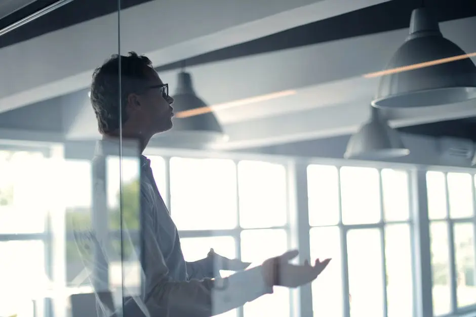 Business professional giving a presentation in a modern office setting through glass.