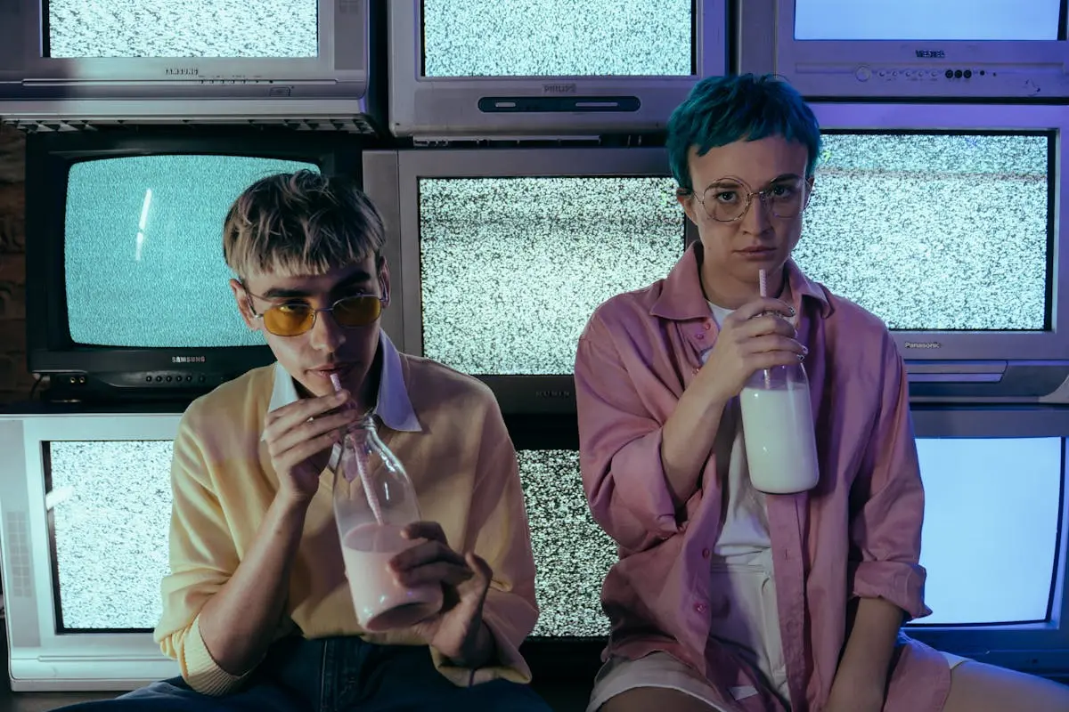 Teenagers sipping milkshakes in front of vintage televisions displaying static. Stylish and retro vibe.