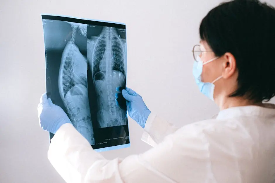 Medical professional in mask and gloves examining a chest X-ray indoors.