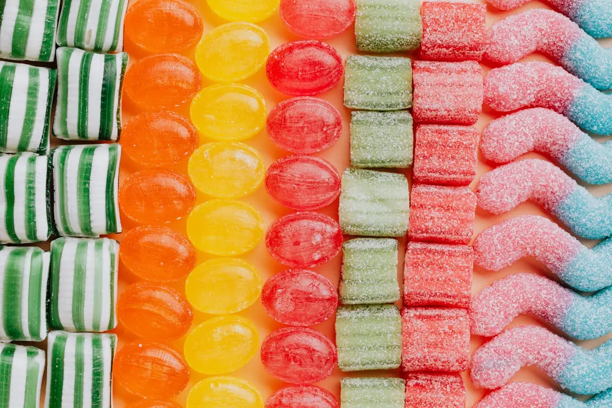 From above of various delicious jelly and caramel sweets arranged in rows by type and color in modern candy store