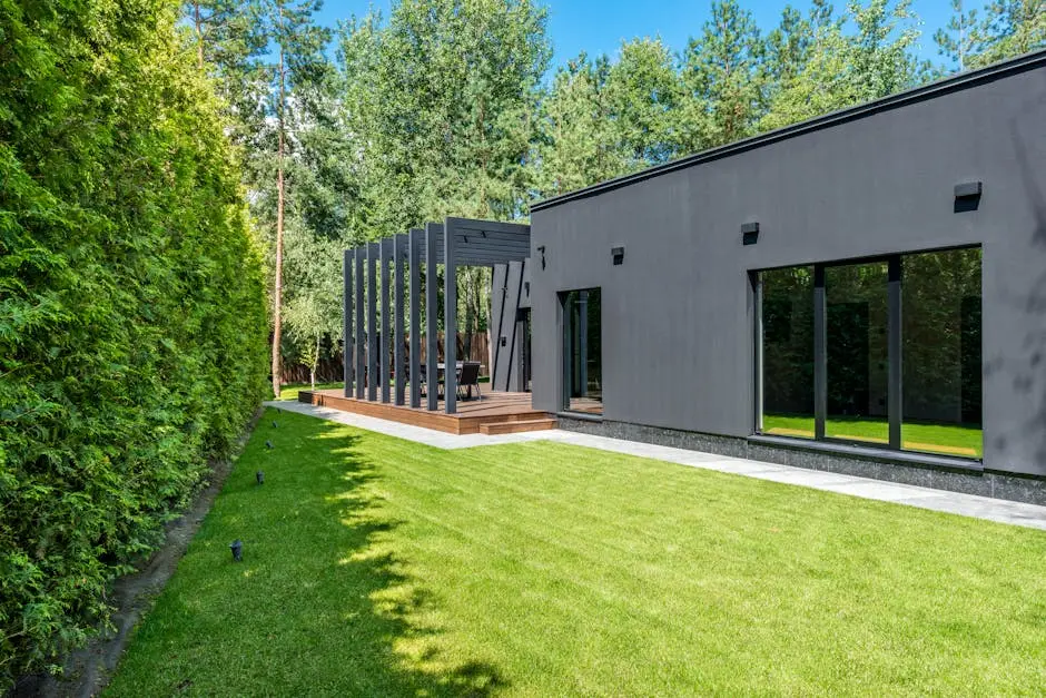 Contemporary house exterior with spacious lawn and pergola, set in a serene outdoor environment.