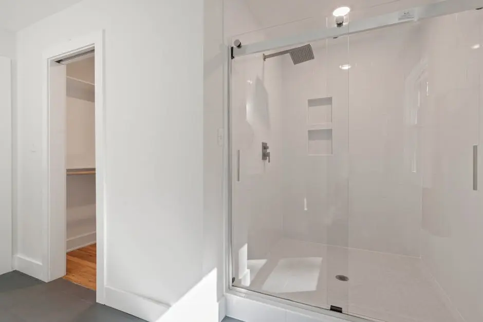 Bright minimalist bathroom interior featuring a glass shower enclosure with sleek design.