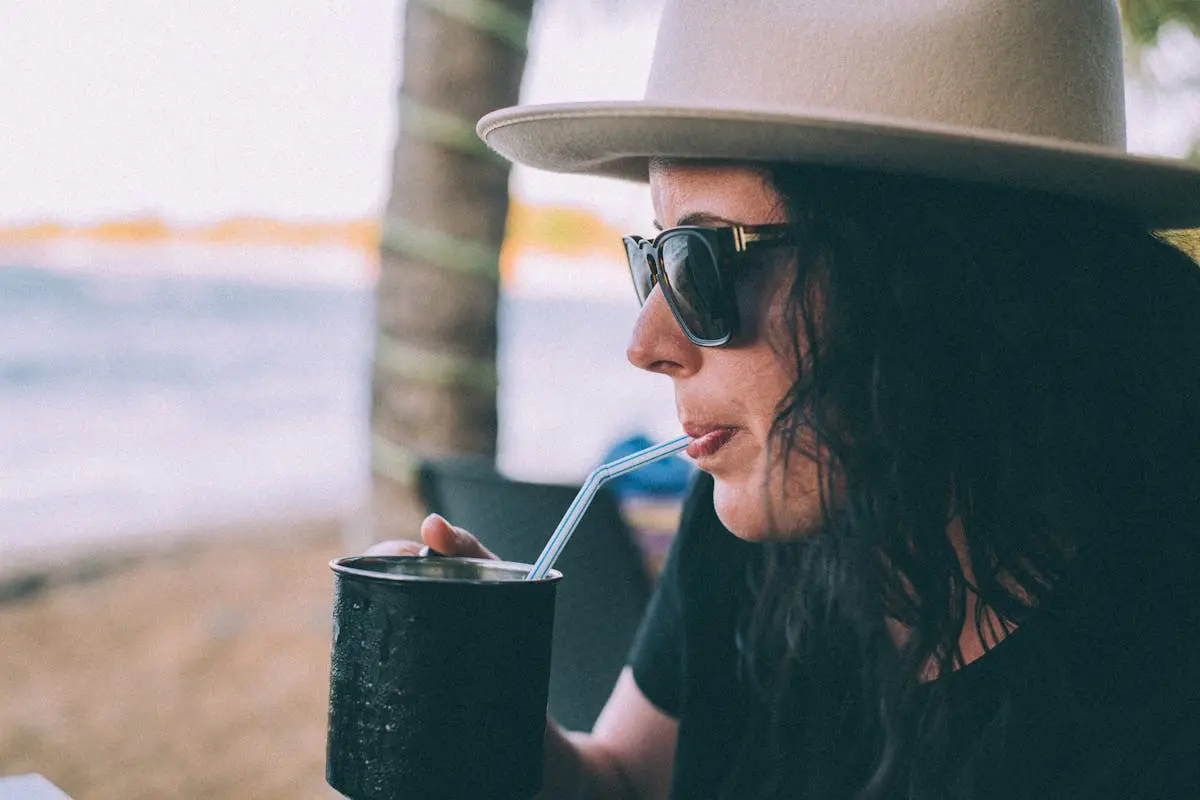 Shallow Focus Photo of Woman Wearing Sunglasses Drinking on Black Cup