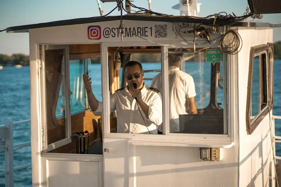 Boat captain uses microphone while navigating on a sunny day at the waterfront.