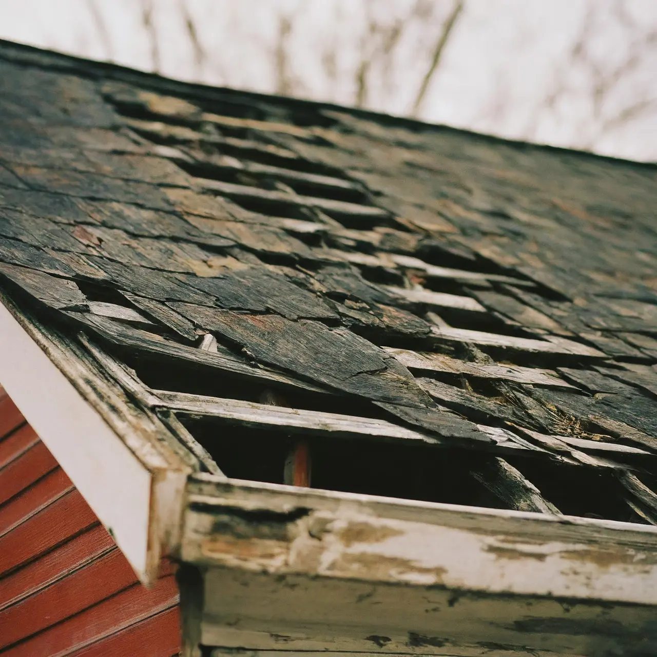 A deteriorating roof with missing shingles on a house. 35mm stock photo