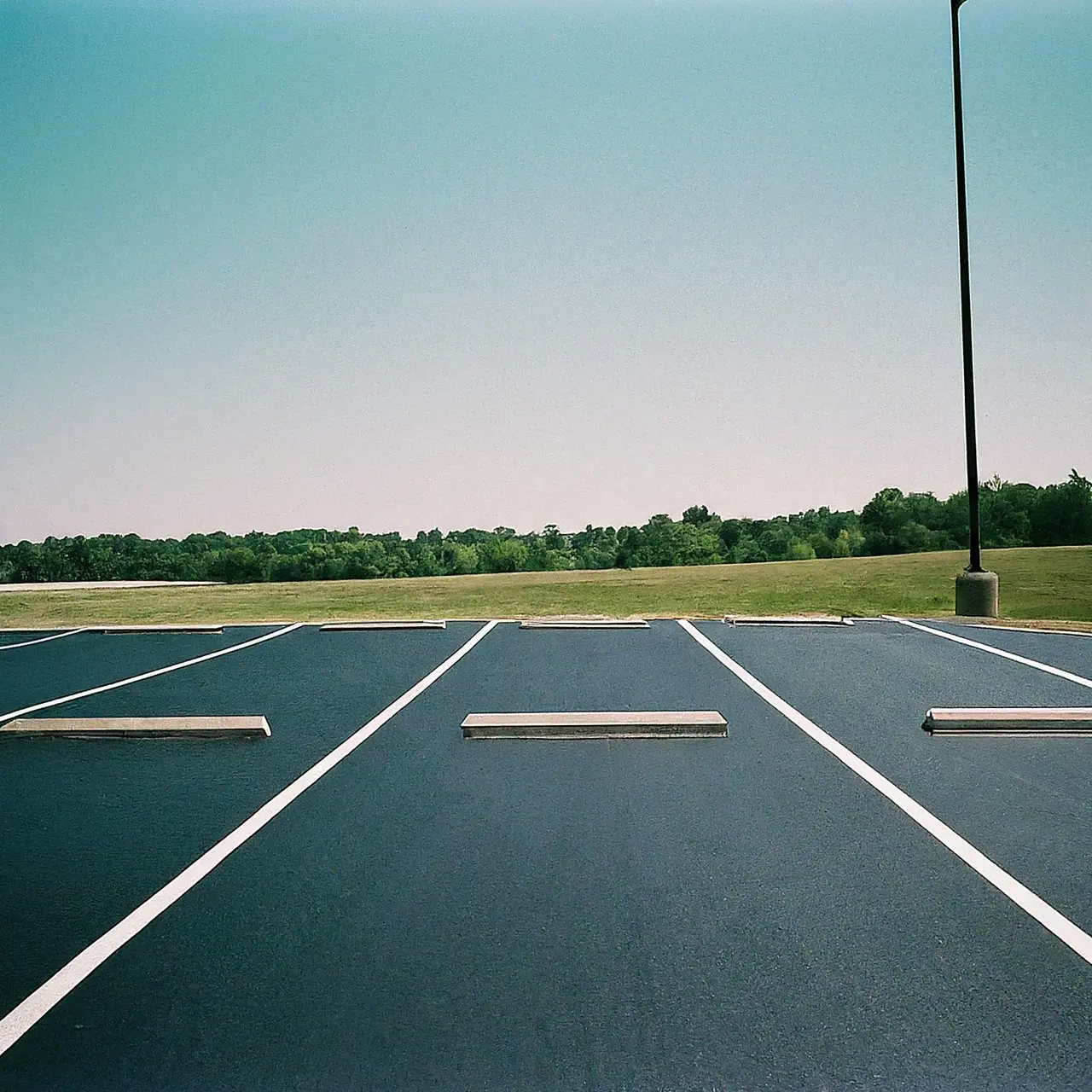 A freshly sealcoated empty asphalt parking lot under a clear sky. 35mm stock photo