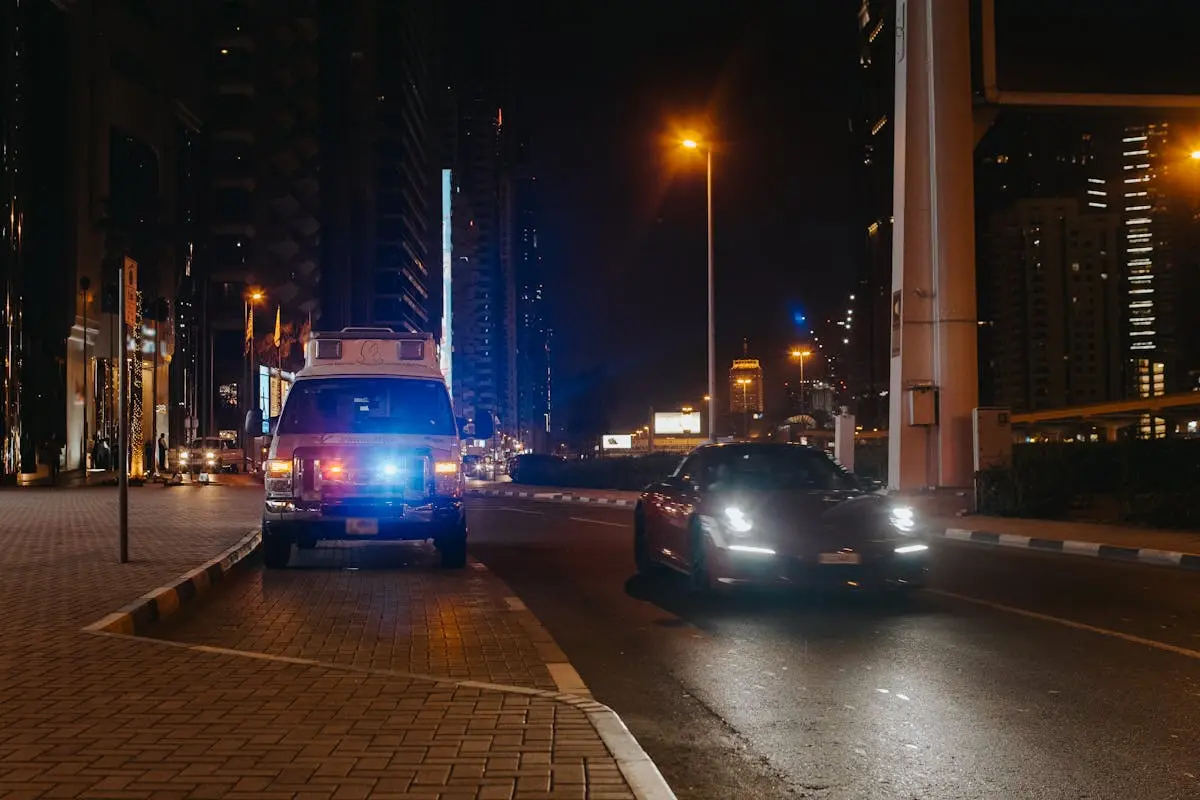 Urban night scene of a city street featuring vehicles and streetlights.