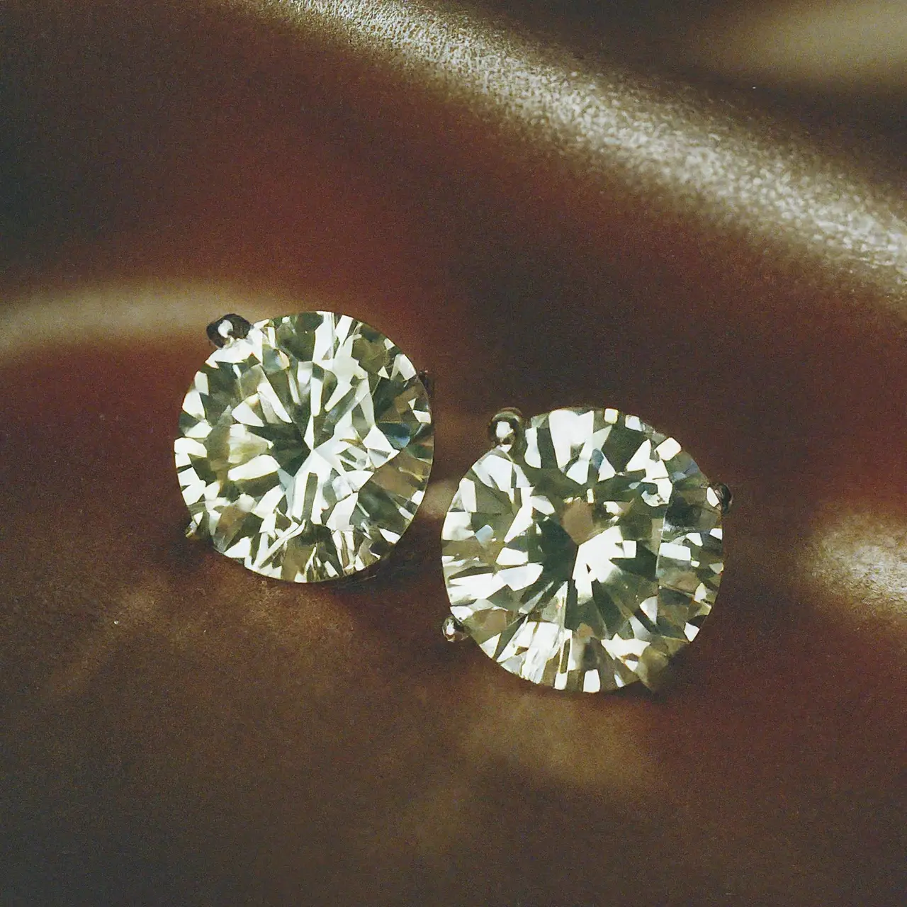 Sparkling 2 carat diamond earrings on a satin pillow. 35mm stock photo