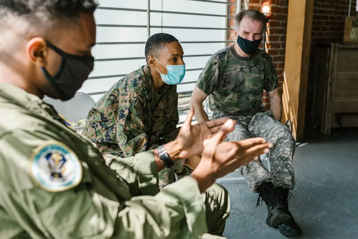 Veterans in military uniform participating in a group therapy session indoors.