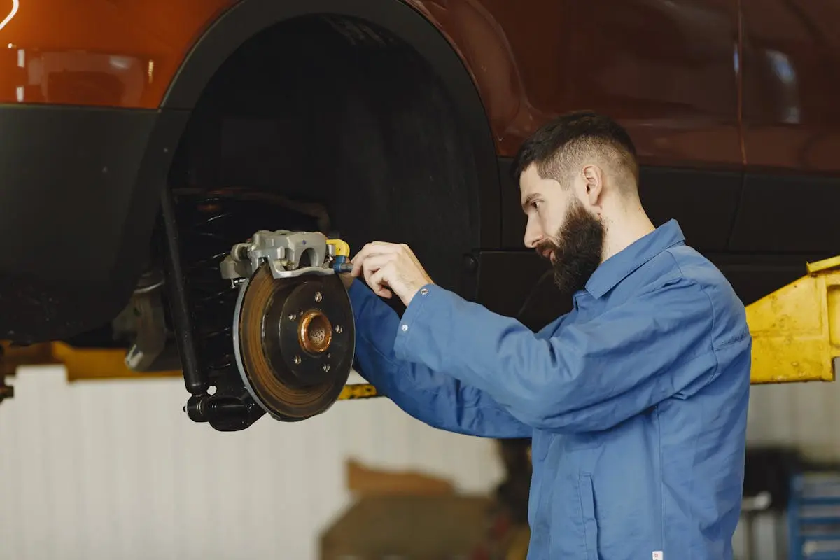 Man in Blue Uniform Fixing the Car’s Brake System