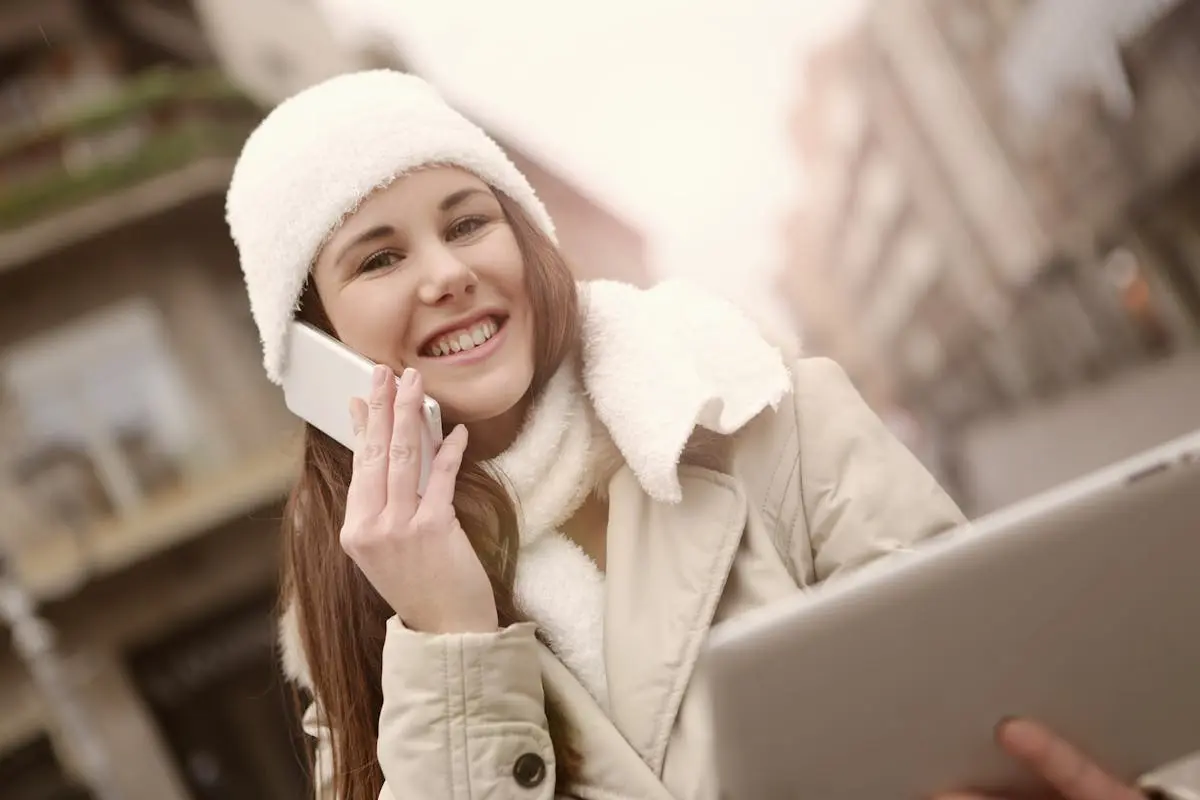 Content woman talking on smartphone and using tablet on street