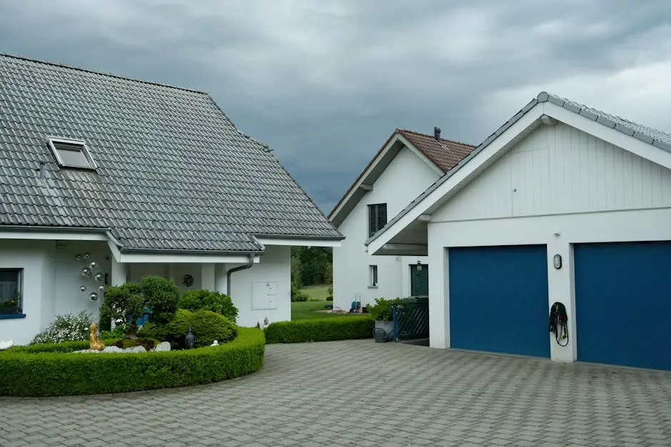 Lovely suburban houses with blue garage doors under cloudy sky, surrounded by greenery.