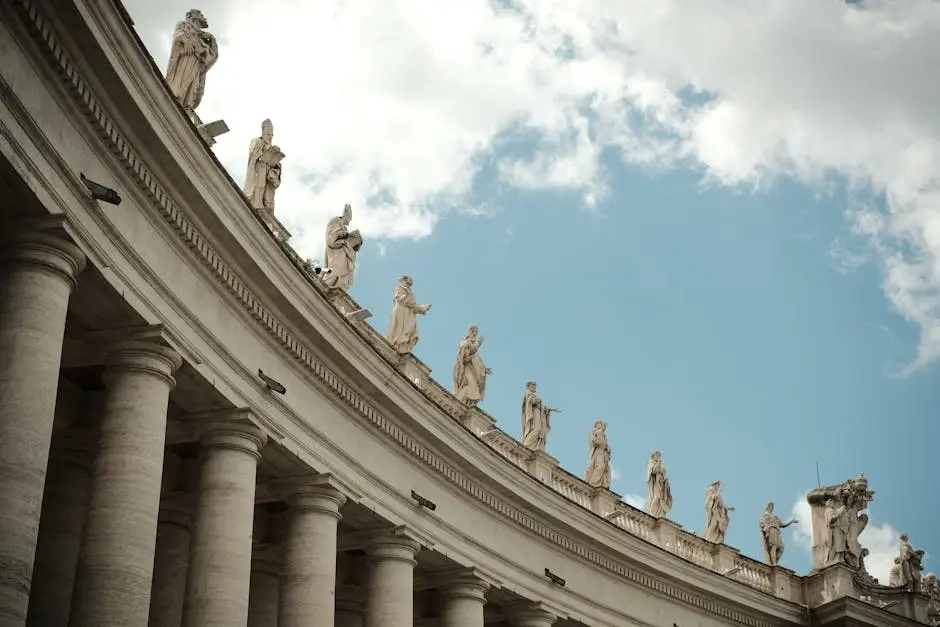 A low-angle view of statues atop columns at St. Peter’s Square, Vatican City.