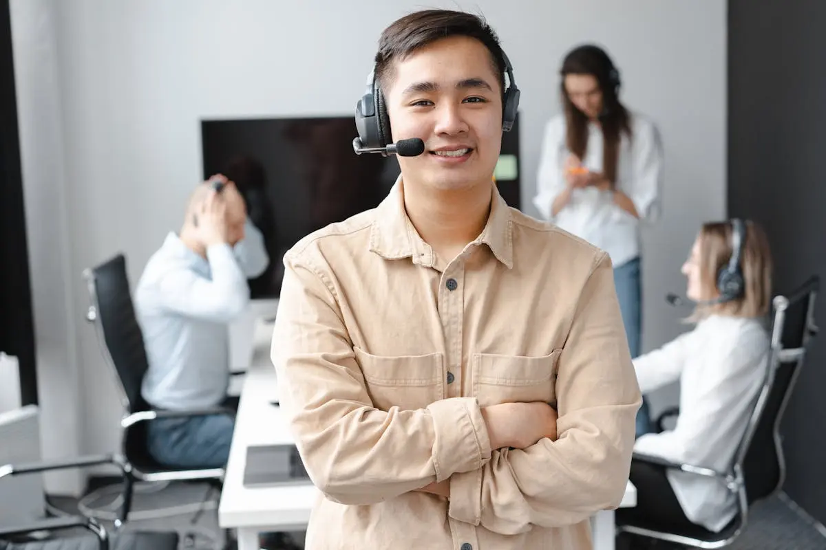 Asian call center agent smiling confidently in a modern office setting.