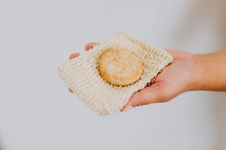 A hand holding eco-friendly handmade soap on a natural loofah pad, promoting sustainable skincare.