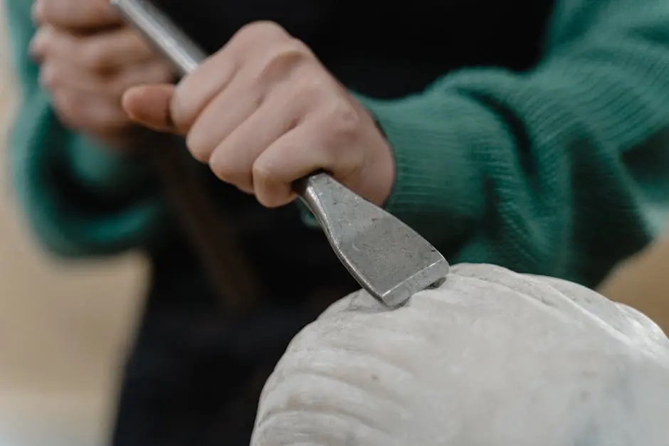 A detailed view of an artisan’s hand engraving a piece of stone with precision and skill.