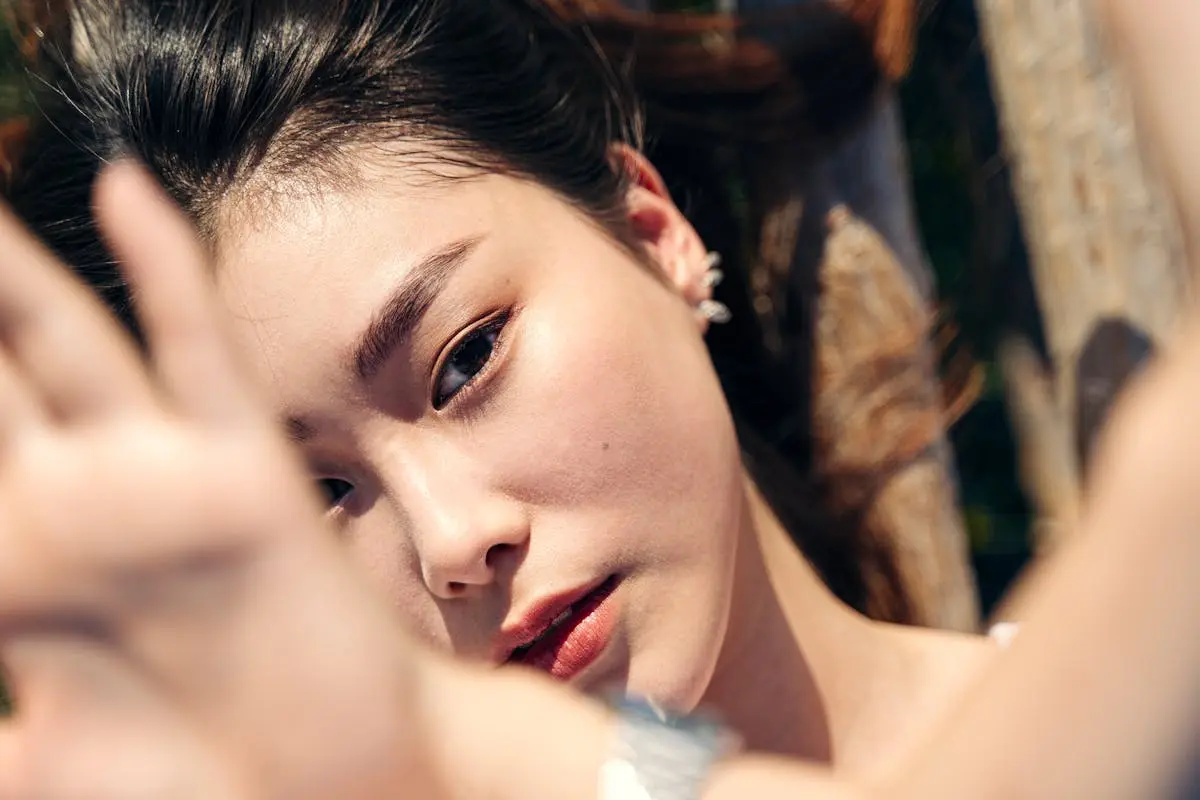 Artistic close-up of a woman’s face with sunlight and hand shading.