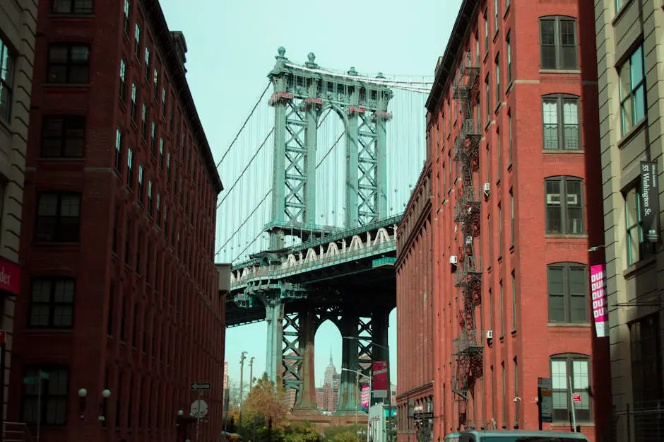 An iconic view of the Manhattan Bridge framed by red brick buildings in Brooklyn, New York.